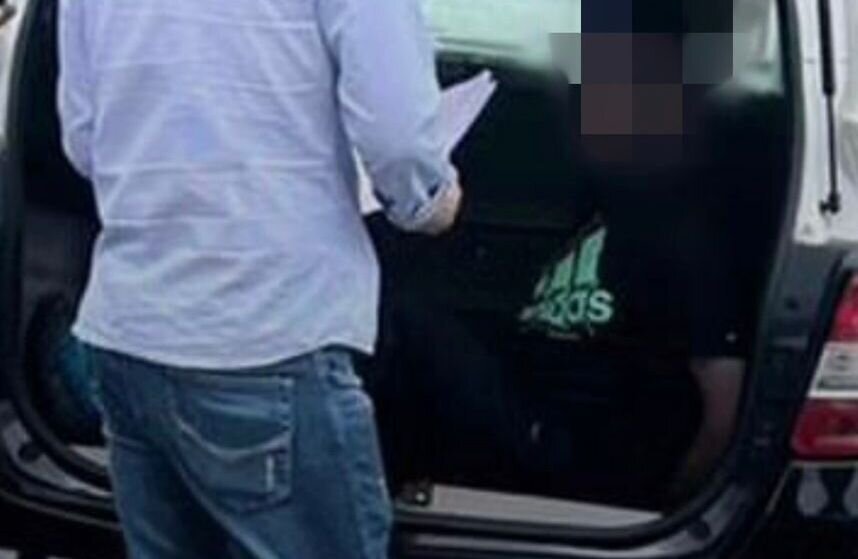 Em foto colorida homem com camiseta preta, na qual há logomarca da Adidas, dentro de carroceria de viatura policial; ele é um professor que foi preso suspeito de estuprar aluna de 9 anos - Metrópoles
