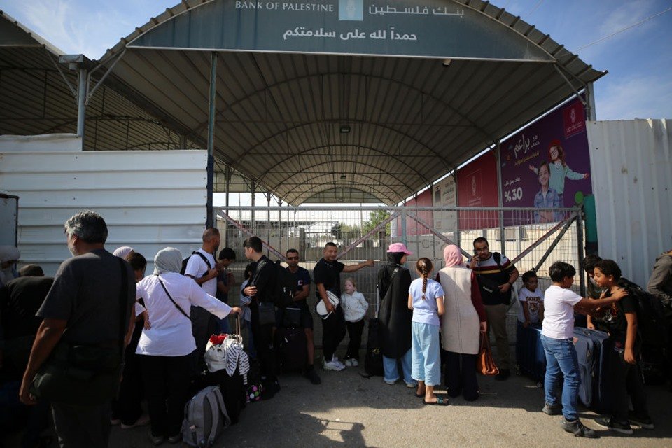 Imagem colorida mostra Palestinos, alguns com passaportes estrangeiros, que esperam cruzar para o Egito na passagem de Rafah, no sul da Faixa de Gaza - Metrópoles