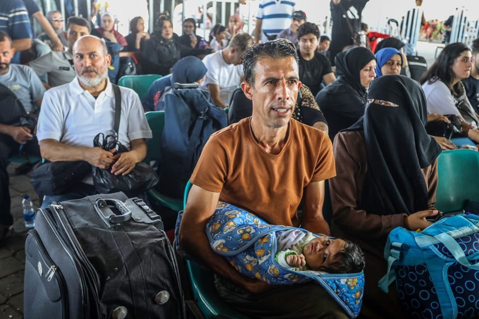 Imagem colorida mostra Palestinos aguardam nome ser chamado para sair de Gaza e entrar no Egito - Metrópoles