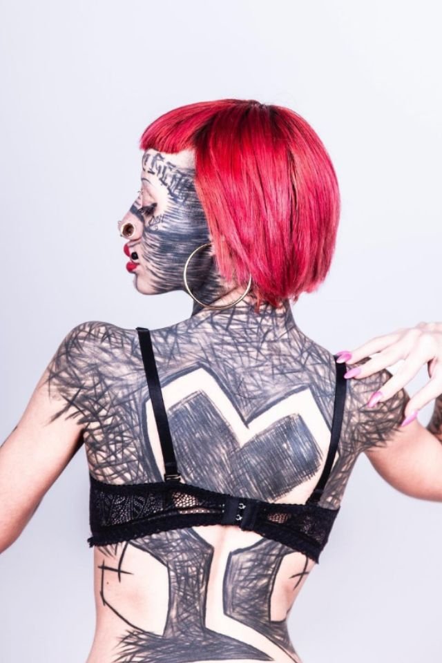 Foto colorida de uma mulher com cabelo vermelho tatuada - Metrópoles