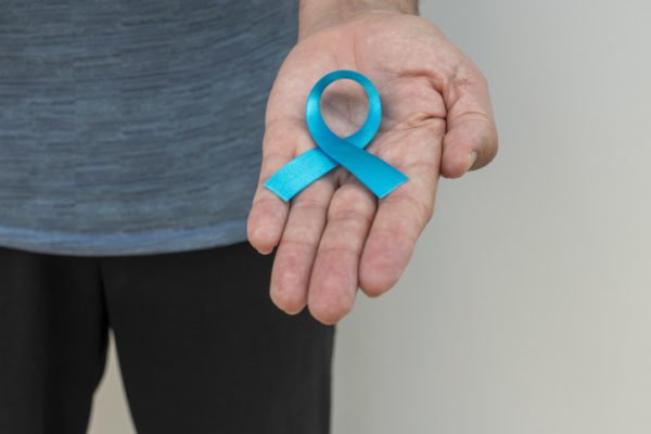 Foto mostra homem segurando fita azul em homenagem ao novembro azul, câncer de próstata