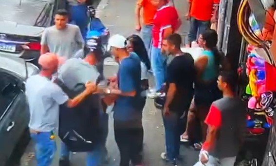 Imagem colorida mostra quadrilha com quatro homens e uma mulher em volta de um motociclista, pegando a mochila do rapaz, que ainda está de capacete; crime ocorreu na rua Barão de Duprat, no centro de São Paulo - Metrópoles