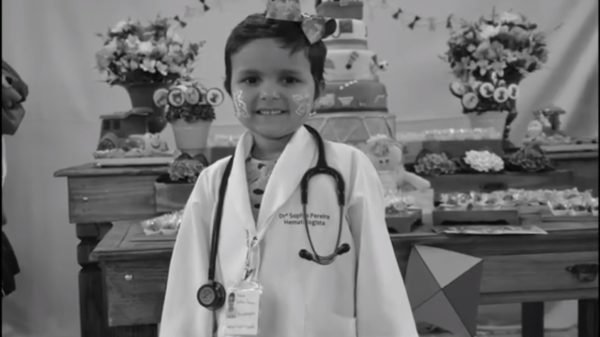 Imagem preto e branca de criança usando jaleco com o própria nome e hematologista - Metrópoles