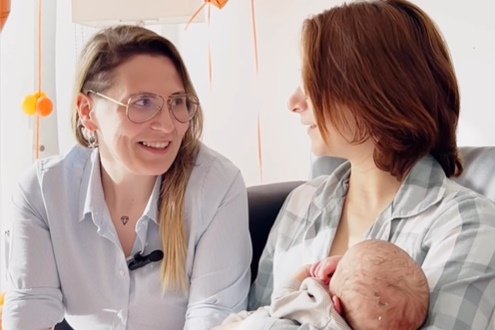 Foto de duas mulheres se olhando com bebê nascido por técnica de reprodução assistida no colo - Metrópoles