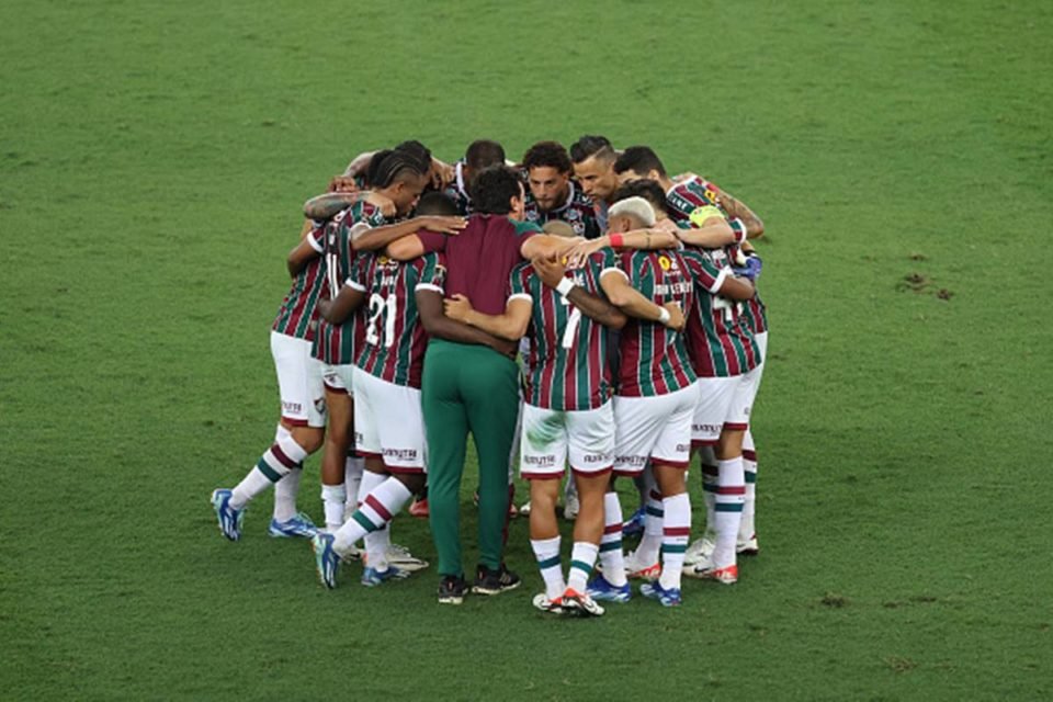 Imagem colorida de jogadores do Fluminense abrabçados em campo - Metrópoles