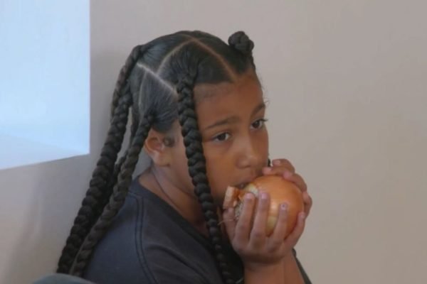 Foto colorida de uma menina comendo cebola - Metrópoles