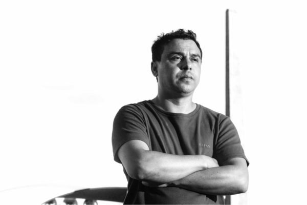 Homem de braços cruzados olha para frente