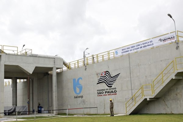 Imagem colorida mostra estação de tratamento de água da Sabesp. A estrutura de concreto cinza na parede tem piso de gramado, em dia de céu encoberto - Metrópoles