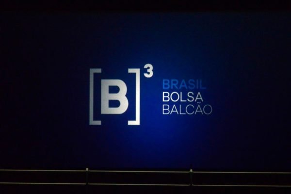Imagem de balcão da Bolsa de Valores do Brasil, a B3, com o logtipo da B3 nas cores azul e branca, um fundo preto - Metrópoles