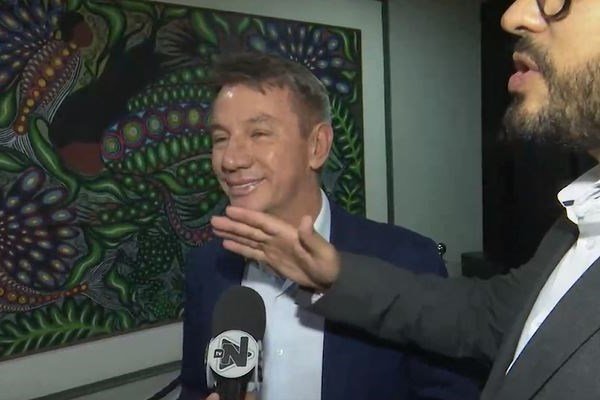 Fotografia colorida de homem sendo entrevistado por jornalista de TV