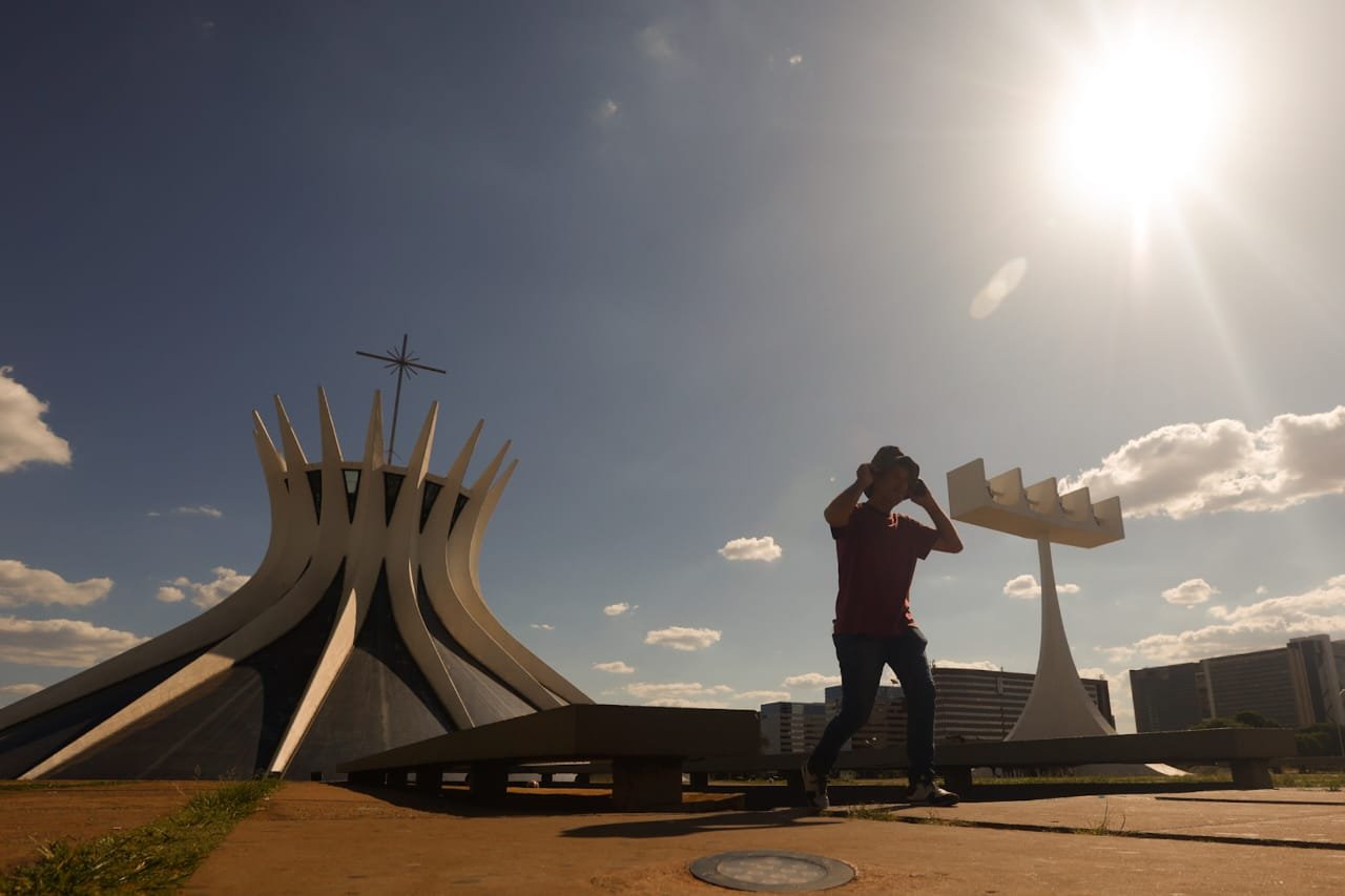 Imagem colorida de homem se protegendo do sol com o chapéu - Metrópoles