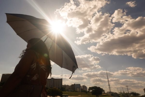 Observatório Imagem colorida de mulher se protegendo do sol com o guarda-chuva calor altas temperaturas - Metrópoles
