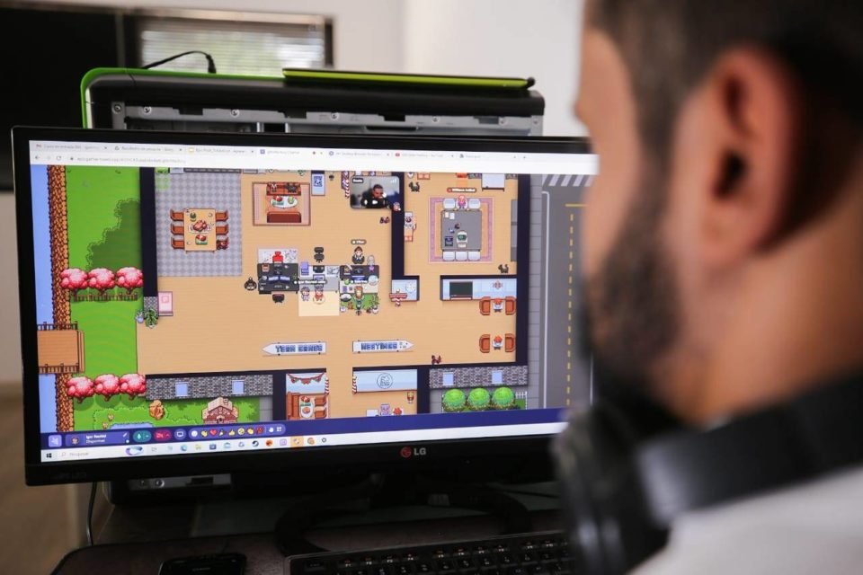 Foto colorida de homem branco com barca olhando computador