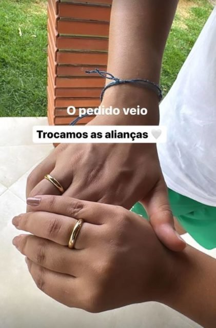 foto colorida com duas mãos com alianças douradas e a frase o pedido veio, trocamos alianças - metrópoles