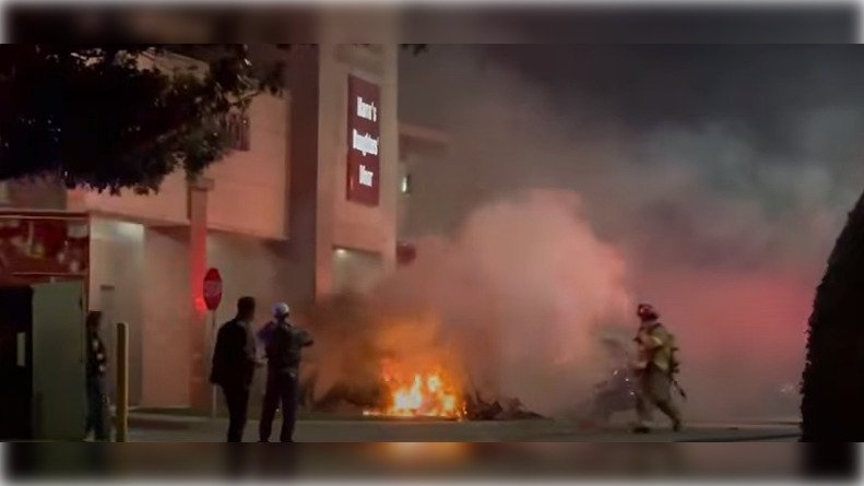 Imagem colorida mostra bombeiros apagando incêndio em avião que caiu em frente a shopping nos EUA - Metrópoles