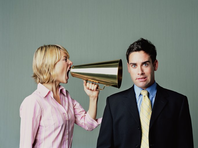 Na imagem colorida, mulher grita para homem usando um megafone - Metrópoles