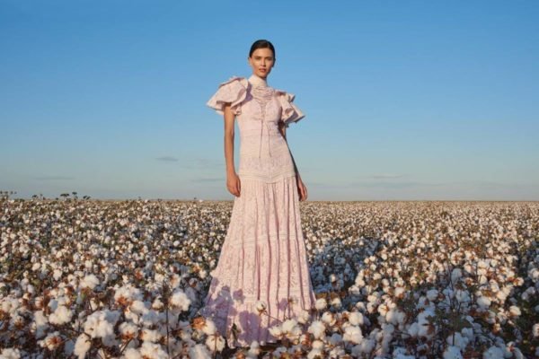 Na imagem com cor, mulher posa em campo de algodão durante o dia ensolarado - Metrópoles