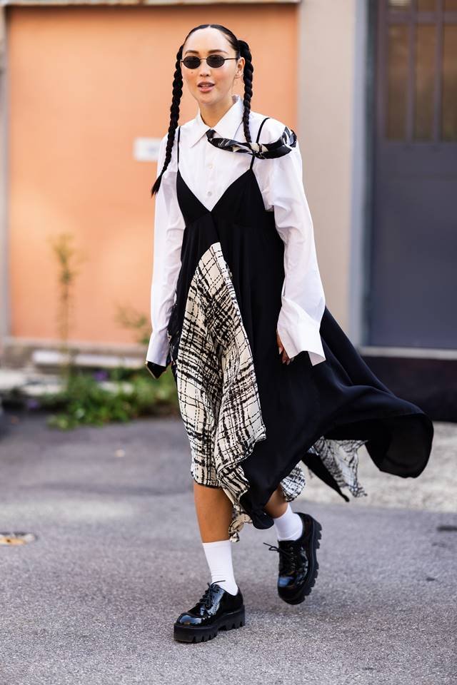 Beim Streetstyle trägt eine Frau ein bedrucktes Kleid über einem weißen T-Shirt.  An den Füßen weiße Socken und geschlossene schwarze Schuhe – Metrópoles