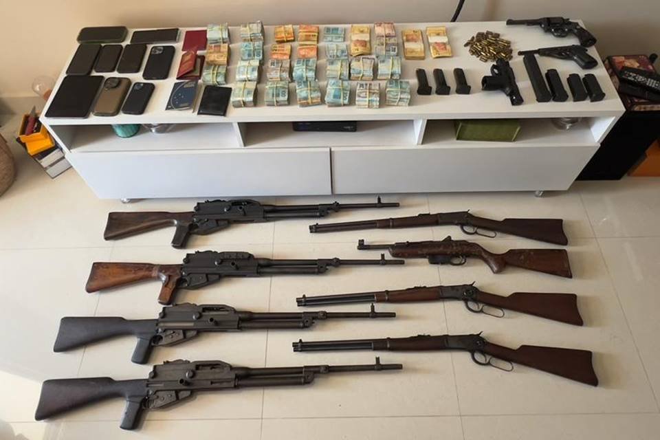 armas no chão e itensroubados e dinheiro vivo em cima de uma cômoda