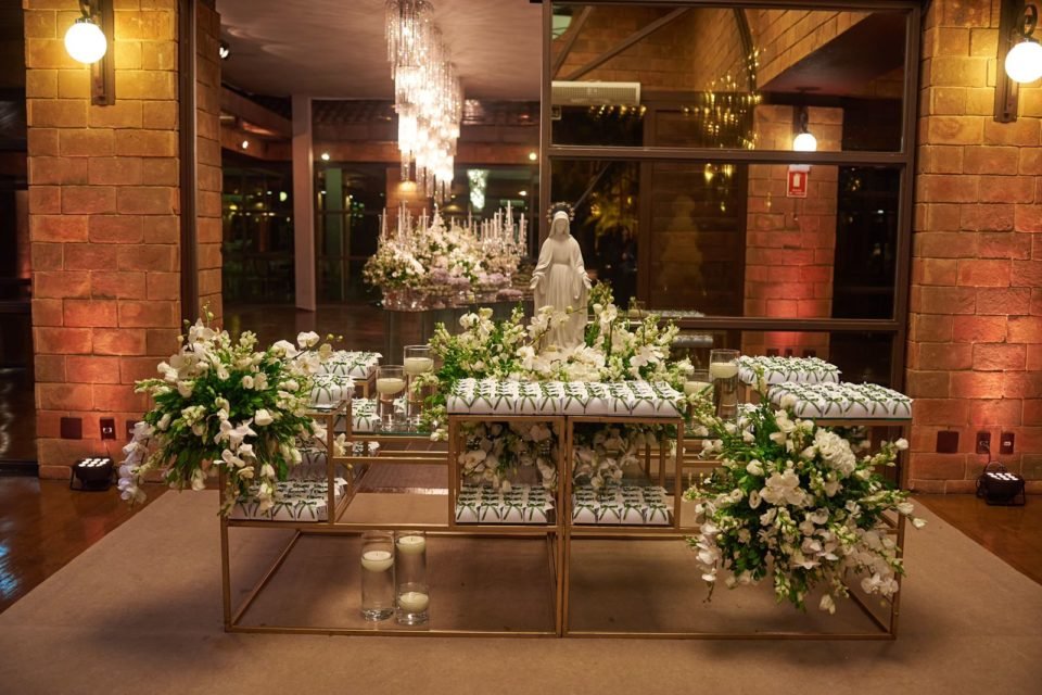 Mesa decorada com flores, bem-casados e a imagem da Nossa Senhora das Graças