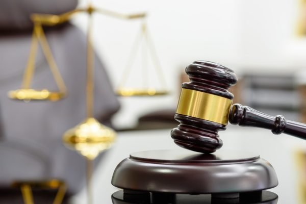 Imagem colorida de um martelo de juiz sendo batido em uma mesa de tribunal - Metrópoles