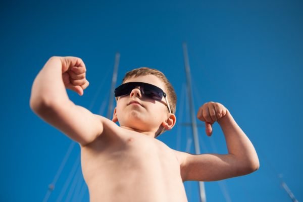 Criança branca mostra os bíceps em foto tomando sol Vitamina d. - Metrópoles