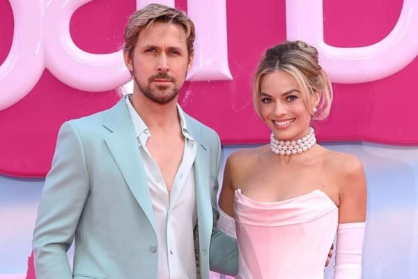 Foto colorida de Ryan Gosling e Margot Robbie lado a lado com a logo do filme Barbie ao fundo - Metrópoles