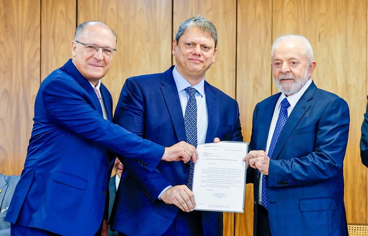 Imagem colorida mostra Alckmin, Tarcísio e Lula, segurando um papel para mostrar aos fotógrafos, no Planalto. Os 3 estão de terno azul - Metrópoles