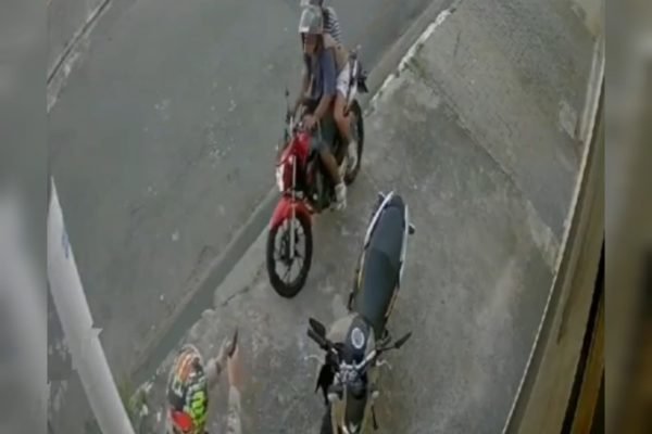 Imagem de homem de capacete apontando arma para dois homens em uma moto; policial penal atirou em dois bandidos, matando um e ferindo o outro - Metrópoles