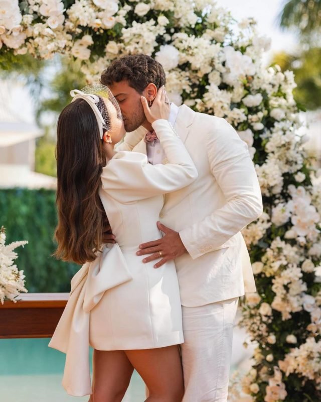 foto colorida de Larissa Manoela e André Luiz Framback vestidos de roupa branca de noivos se beijando - metrópoles