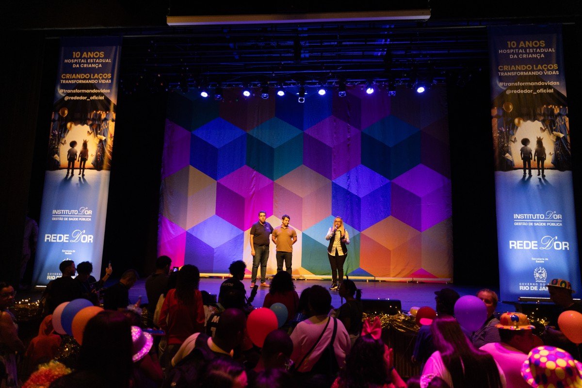 Fotografia colorida mostrando três pessoas em palco-Metrópoles