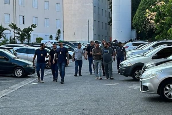 Imagem mostra homens caminhando em estacionamento; um deles é um homem preso por matar um policial em 2017 que já havia sido condenado pela Justiça - Metrópoles