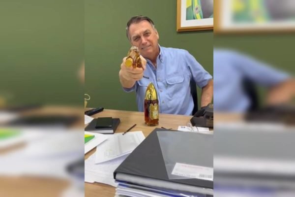Fotografia colorida mostra homem empunhando garrafa de vidro em formato de arma de fogo