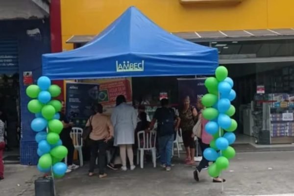 Imagem colorida de tenda da Ambec, associação de aposentados, em calçada em frente a uma farmácia - Metrópoles