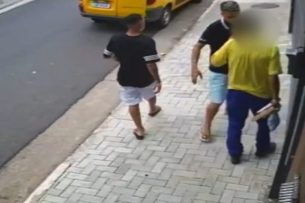 Imagem de dois homens ameaçando funcionário dos Correios em calçada - Metrópoles