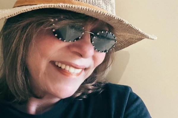 Gloria Perez posa, sorridente, de chapéu e óculos escuros - Metrópoles