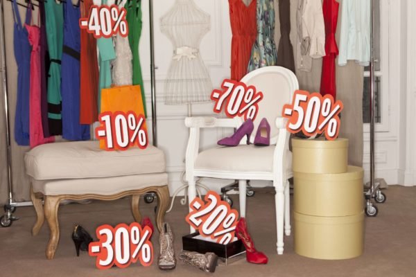 Imagem de placas com promoção e roupas em lojas - Metrópoles