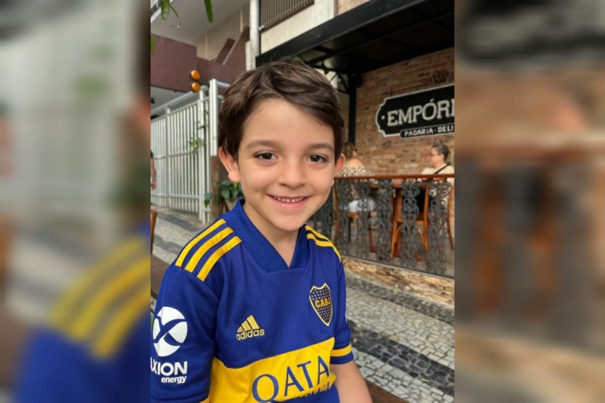 Foto mostra menino branco de cerca de seis aos olhando para a c&acirc;mera e sorrindo