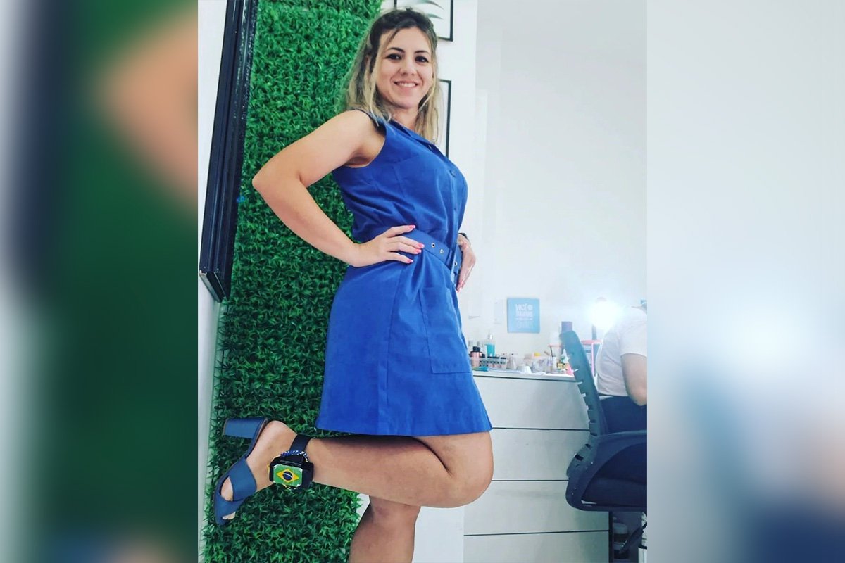Foto colorida de Roberta Brasil, de vestido azul e tornozeleira eletrônica com a bandeira do Brasil. Ela foi presa por participar dos atos golpistas de 8/1 - Metrópoles