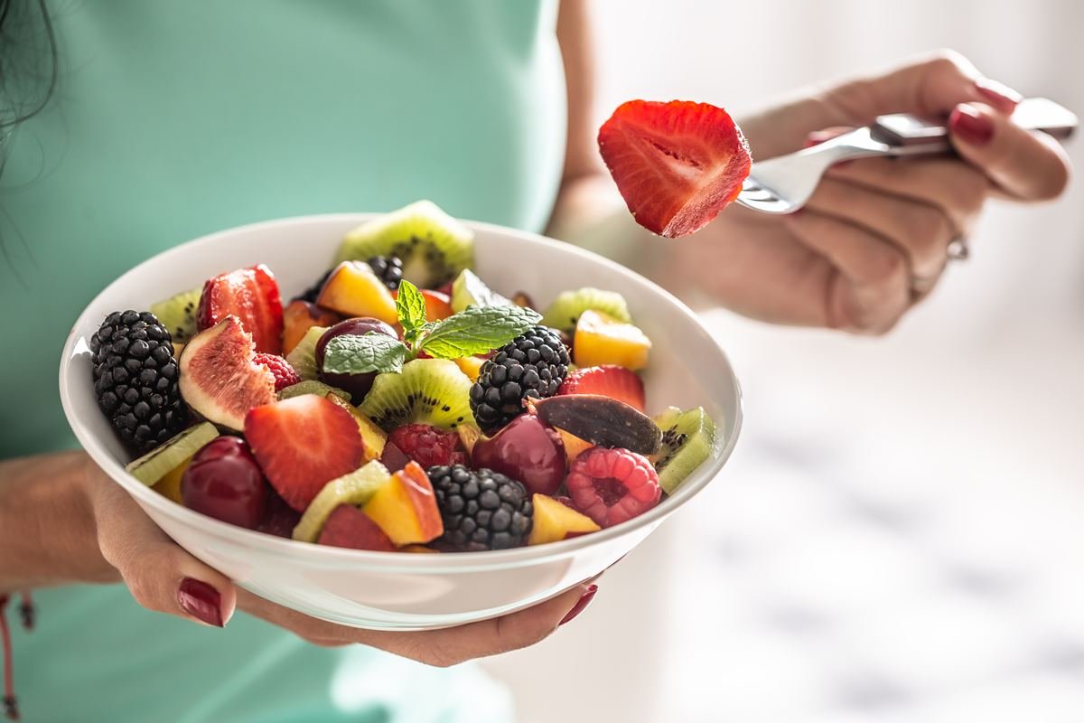 Uma mulher segura uma tigela branca com salada de frutas rica em vitaminas e fibras - Metrópoles