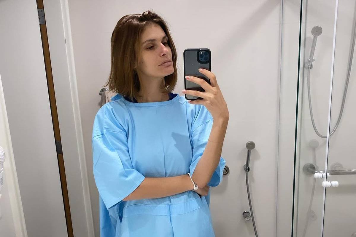 Foto colorida de Caroline Francischini em hospital, usando roupa e pousando para foto em espelho - Metrópoles