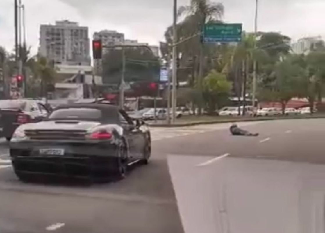 Imagem colorida de homem armado e Porsche preto em rua do Rio de Janeiro - Metrópoles