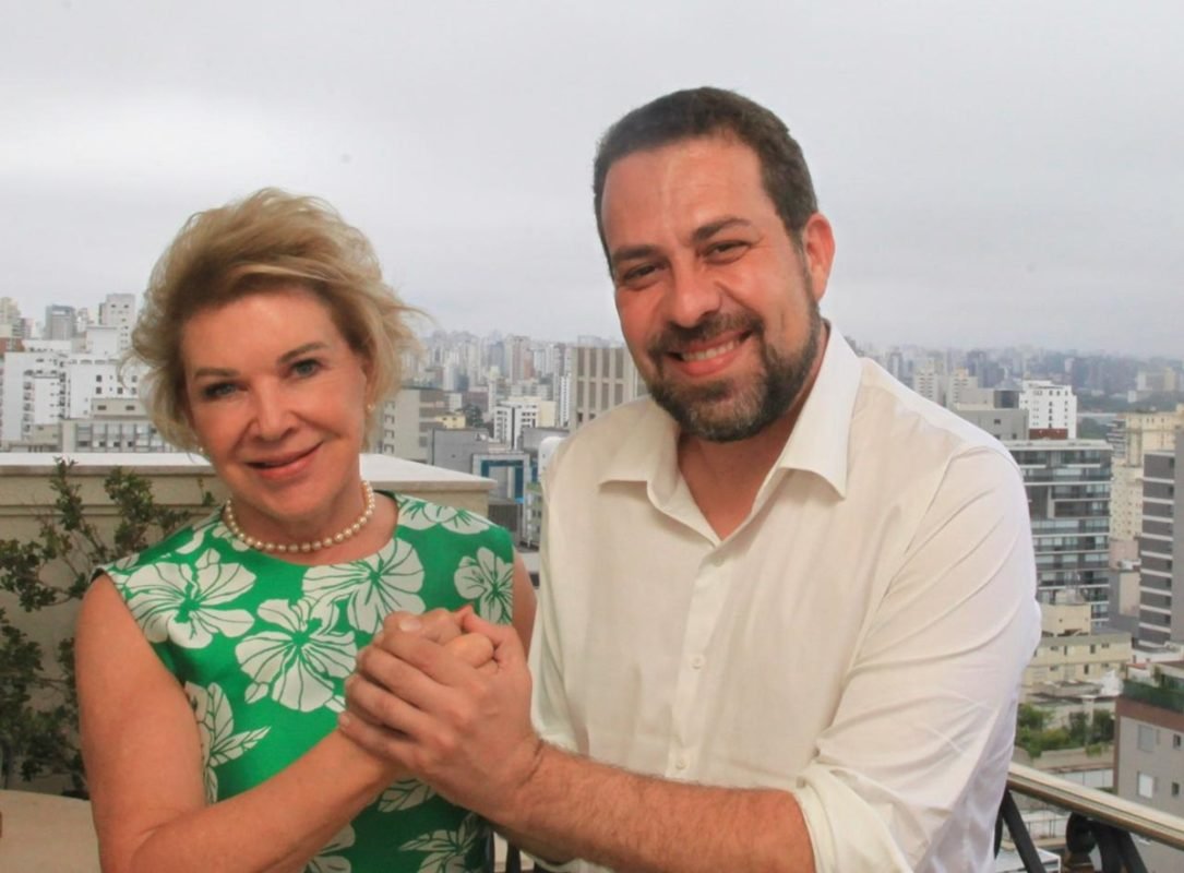 Imagem colorida mostra Marta Suplicy, mulher branca, loira, de olhos azuis, de braços dados com Guilherme Boulos, homem branco, de cabelo, barba e olhos castanhos - Metrópoles