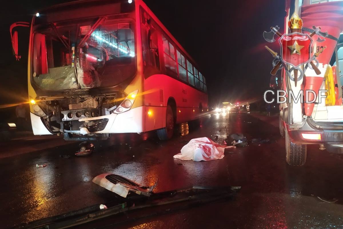 foto avermelhada de onibus batido ao lado de viatura dos bombeiros e corpo no chão coberto com lençol - metrópoles