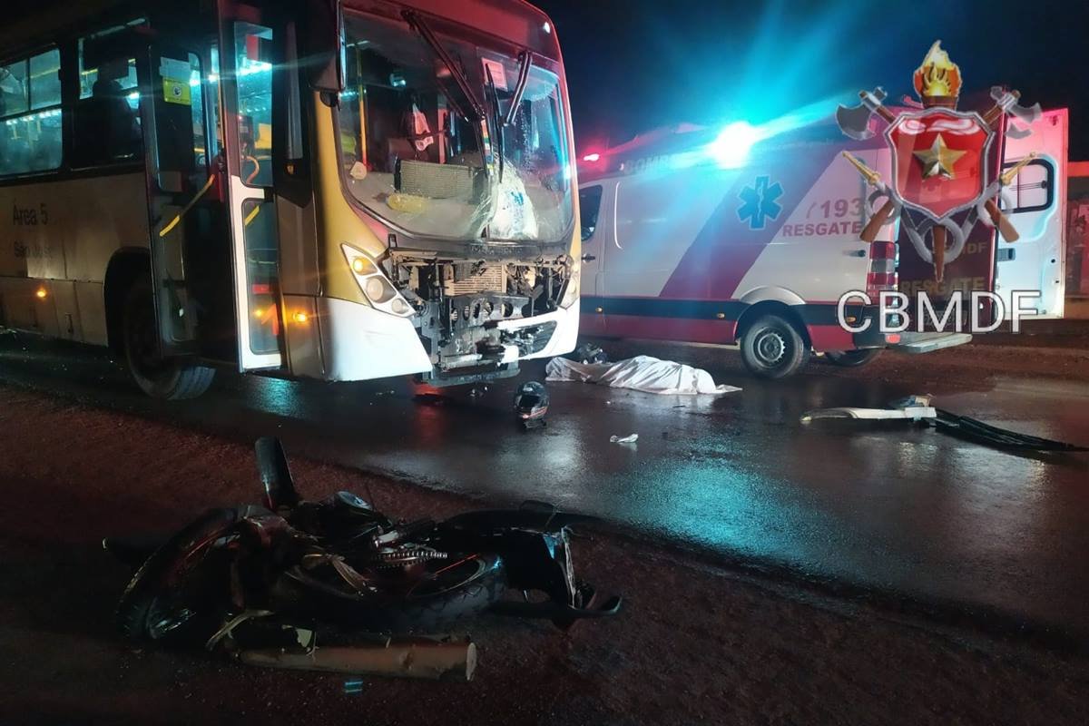 foto avermelhada de onibus batido ao lado de viatura dos bombeiros e corpo no chão coberto com lençol - metrópoles