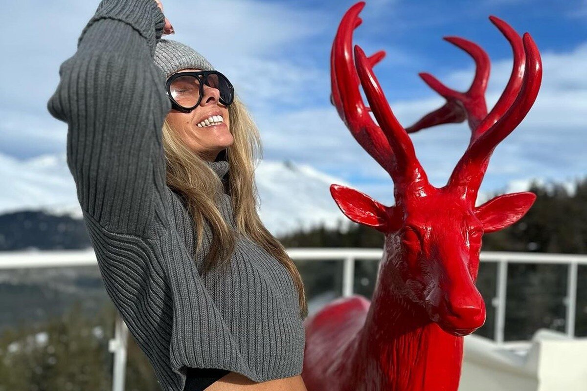 Adriane Galisteu posa, sorridente, ao lado de um alce vermelho na Suíça - Metrópoles