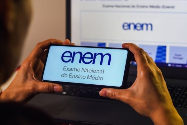 Imagem de pessoa segurando um telefone com a logo do Enem - Metrópoles