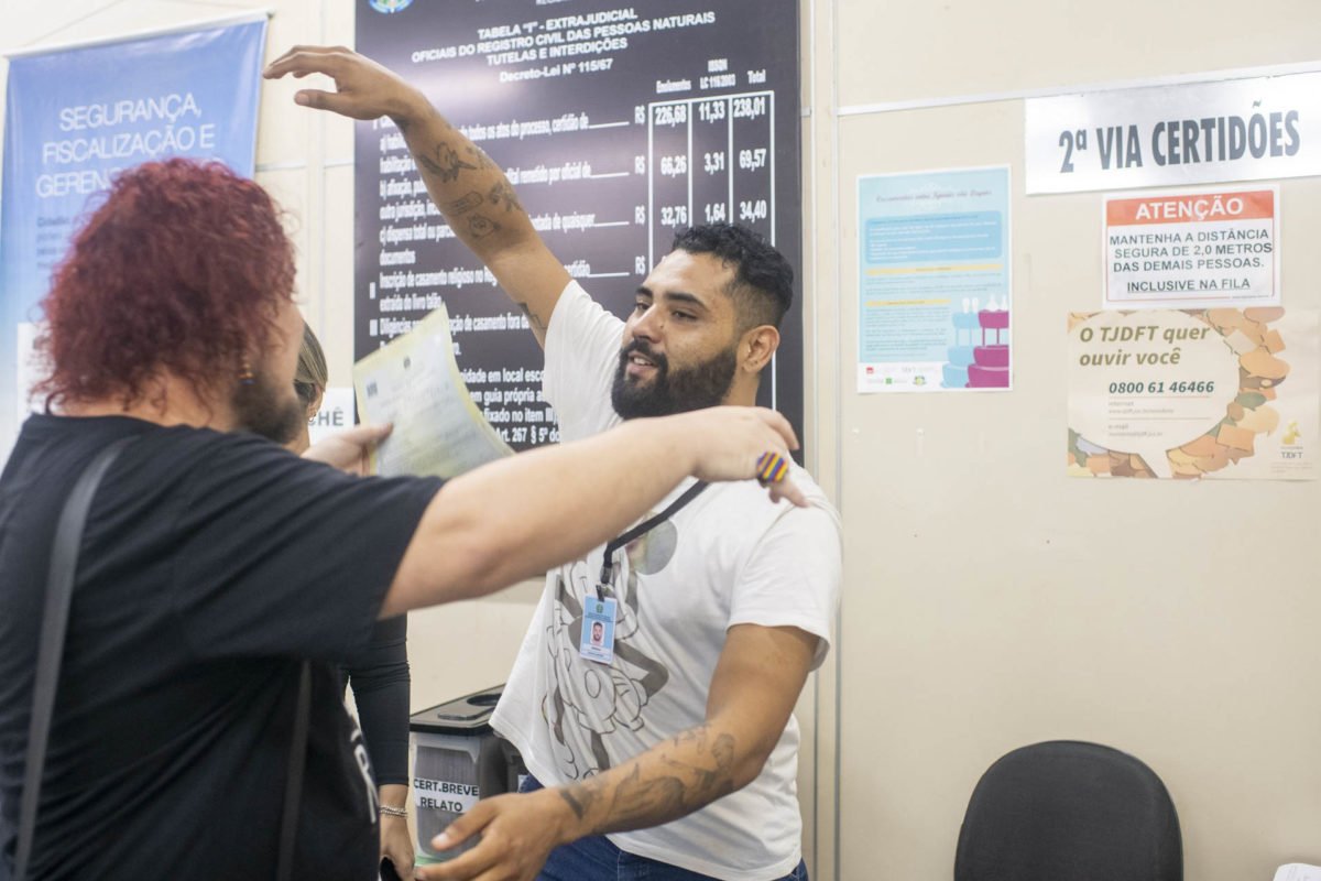 Homem branco de cabelo pintado de ruivo abraçando homem pardo e barba feita