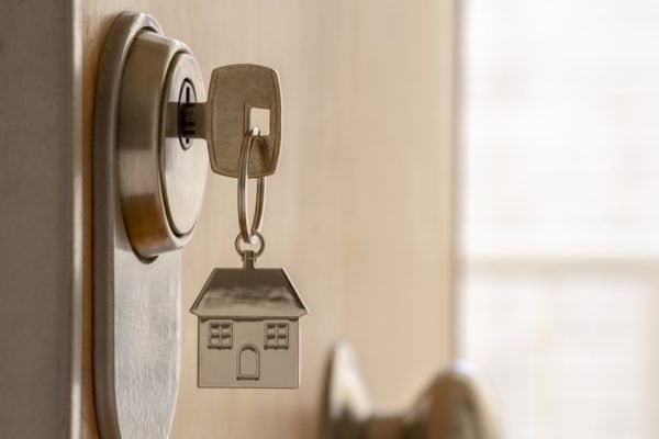 Imagem de chaveiro em formato de casa, com chave abrindo uma porta de um apartamento - Metrópoles
