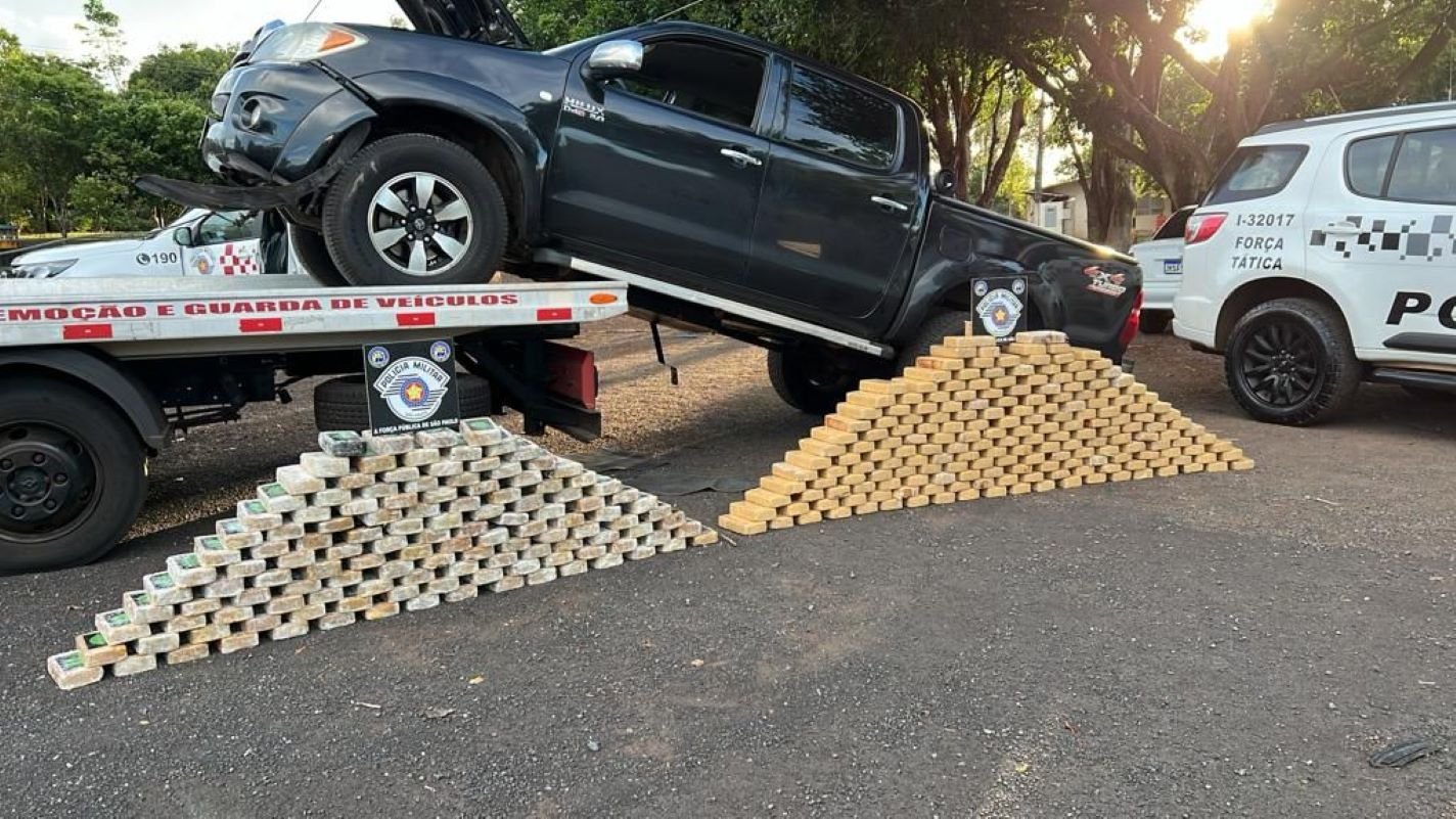 Imagem colorida mostra pacotes de drogas na frente de um carro apreendido pela Polícia Militar (PM); um agente da PRF foi detido - Metrópoles